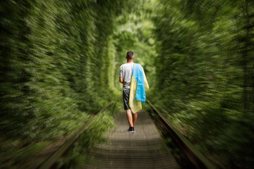 man raised his hands and holds the Ukrainian flag behind his back. concept Ukrainian patriot, rally...