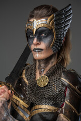 Shot of valkyrie dressed in ancient dark armor holding sword on her shoulder.