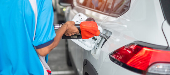 Man hand refuel to car, gasoline fuel nozzle in vehicle at petrol station. Oil Price, petroleum economy, inflation and commodity concept
