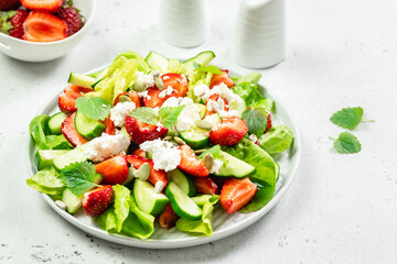 Healthy summer strawberry cucumber spinach feta cheese salad. Top view, copy space, flat lay.