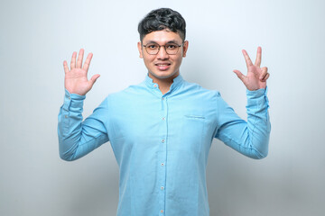 Fototapeta premium Young asian man wearing casual clothes showing and pointing up with fingers number while smiling confident and happy