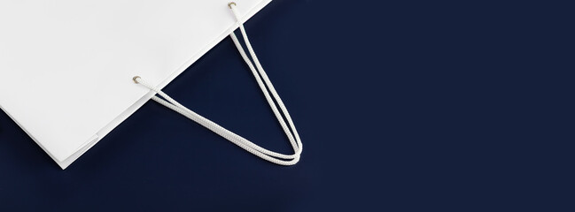 Minimalistic banner with White paper gift bag on a deep blue background with copy space. Concept of sale and shopping. Banner size