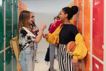 Young high school students meeting and greeting near locker in campus hallway, back to school...