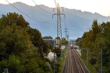 power lines and railway in a Swss valley with mountains in the background