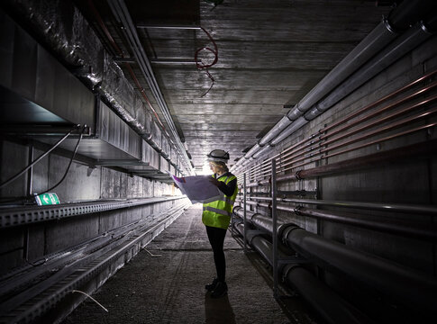 Young engineer looking at blueprint standing in tunnel