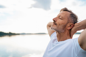 Mature man relaxing with eyes closed at lake