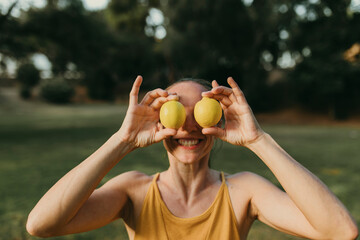 Smiling woman holding lemons in front of face