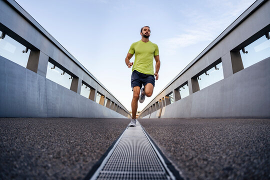 Young man running on footbridge