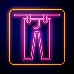 Glowing neon Drying clothes icon isolated on black background. Clean pants. Wash clothes on a rope with clothespins. Clothing care and tidiness. Vector