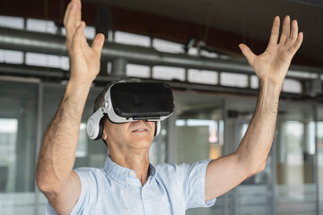 Mature businessman wearing virtual reality simulator gesturing in office
