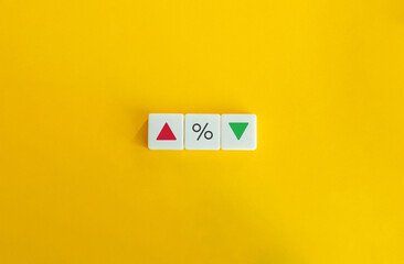 Interest Rate Concept. Red Arrow, Percentage Sign, and Green Arrow on Block Letter Tiles on Yellow Background. Minimal Aesthetics.