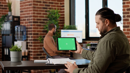 Male freelancer using horizontal greenscreen display on tablet, looking at blank chroma key template with isolated mockup background and copyspace. Digital gadget with technology.