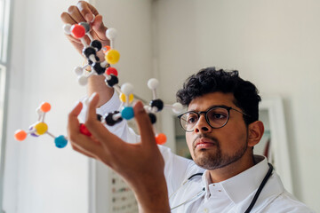 Young scientist analyzing helix model in laboratory
