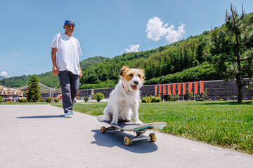 Smiling man with dog sitting on skateboard in park