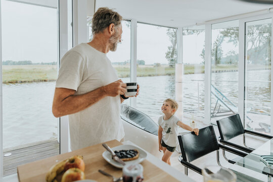 Happy son with father holding coffee cup at home