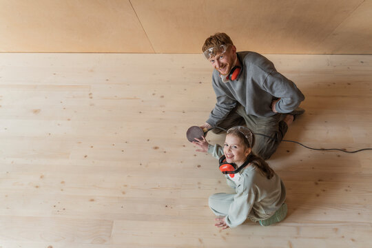 Father and daughter sanding the floor in their new eco house