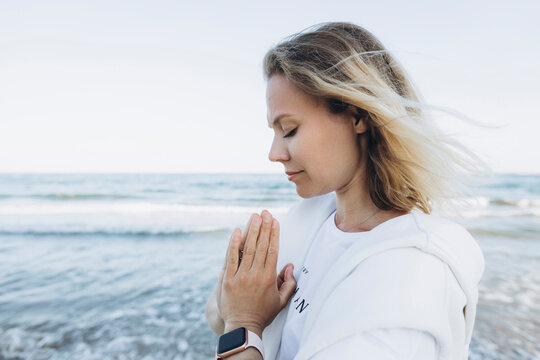 Woman with hands clasped in front of sea