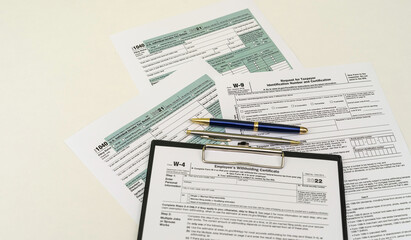 Fototapeta premium top view of tax forms on tablet on office desk with calculator and pen.