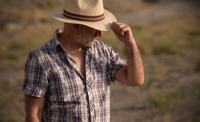 Fototapeta premium Portrait of adult man in sun hat and shirt in desert
