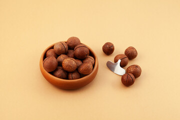 Macadamia nuts on beige background. Selective focus, copy space. Macadamia is delicious nut with hardshell