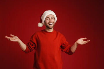 Young smiling man wearing santa hat holding copyspace