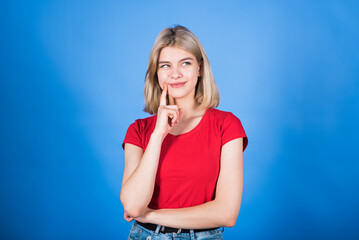 Young and attractive blonde caucasian girl in casual clothes holding a finger to her lips, smiling...
