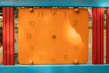 Orange pointless clock written on a wood on an outdoor park