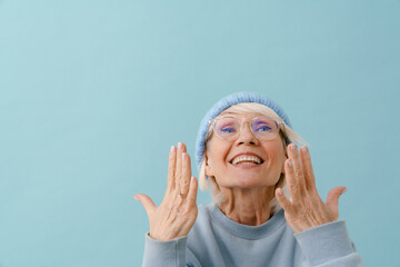 Beautiful enthusiastic senior woman with raised hands looking upward