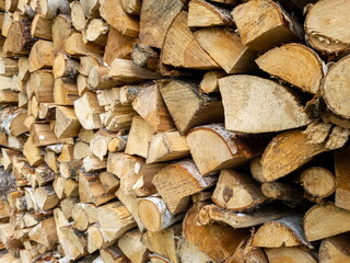 Dry birch firewood stacked in a neat woodpile. A supply of wood for kindling the fireplace.