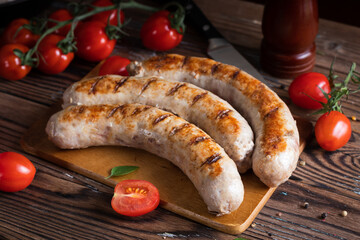 Fried sausages with tomatoes on cutting board. Soft focus