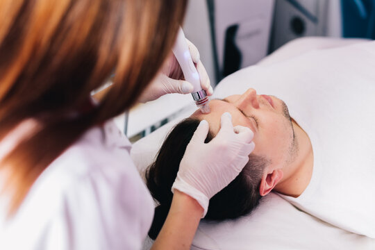 Cosmetologist Doing Hydrafacial Treatment On Man Face