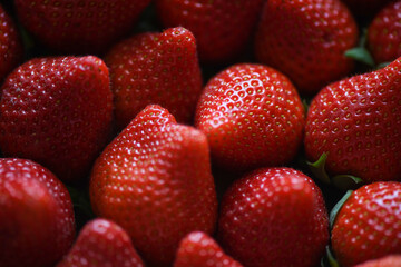 Delicious strawberries filling a small wooden crate, close-up of the red and juicy fruit with shiny skin and small seeds, favorite berries for the fresh aroma, versatility and high nutritional values