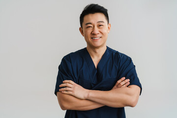 Adult asian man wearing medical uniform posing at camera - obrazy, fototapety, plakaty