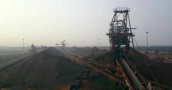 Stacker Reclaimer Machines, Dump Trucks, And Stockpile Of Iron Ore At The Coal Handling Area Of Paradip Port In Odisha, India. aerial drone