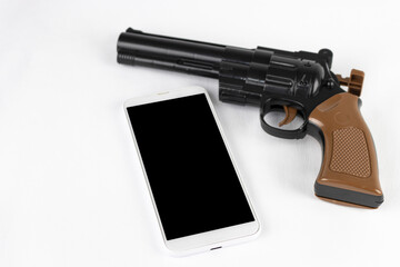 玩具の銃と、スマートフォン。犯罪予告のイメージ