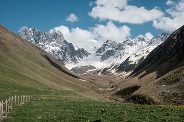 Georgia, Caucasus Mountains, Juta valley - cold river, blue sky, mountain from stones and snowy peak Chaukhebi in summer.