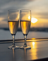 Two glasses with champagne on window on sunset