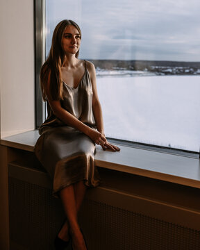 Young woman resting at hotel, sitting on the window sill enjoying beautiful view