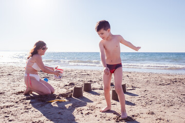 mom and son play at the beach making a sand castle together