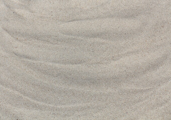 Fototapeta na wymiar Sandy beach background, wavy sand, top view. Abstract sand texture close up. Summer concept.