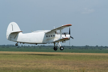 An An-2 airplane taking of from the grass airfield. Side view.