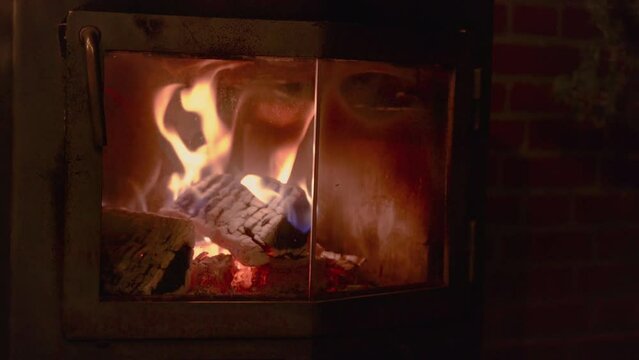 Fire burning in a steel outdoor stove behing a glass door