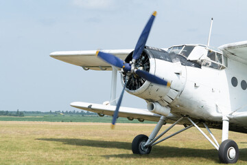 Fototapeta na wymiar An An-2 airplane starts its engine on the grass airfield. The propeller starts rotating. Front view.