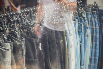 Display window of a clothing shop with a reflection of passing tourists at Brick Lane market in London