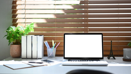 Mock up laptop computer, books, stationery and houseplant on white table