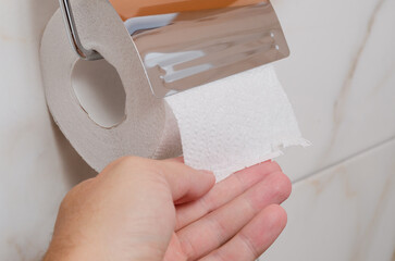 hand tearing off toilet paper