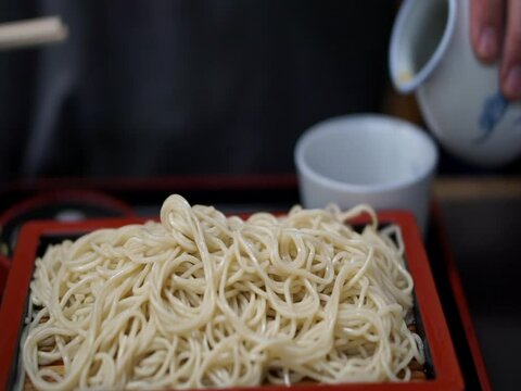 Asian man eating Japanese fresh made somen noodle with dashi soy sauce soup and leek