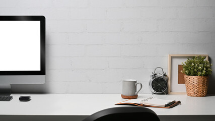 Comfortable home office desk with computer pc, coffee cup, picture frame an houseplant
