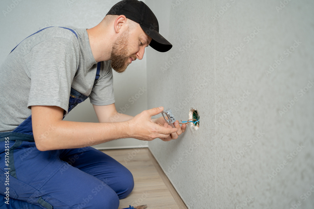 Wall mural caucasian man electrician holding screwdriver working on the plug electric on residential electric s