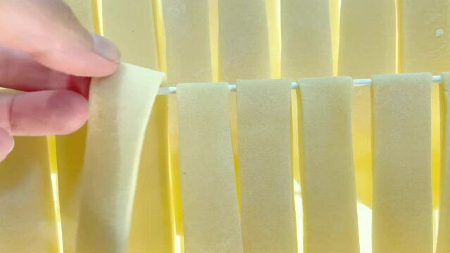 Closeup Drying pappardelle pasta on a rope. Uncooked fresh pasta. Pappardelle are large, very broad, flat pasta, similar to wide fettuccine, originating from the region of Tuscany.
